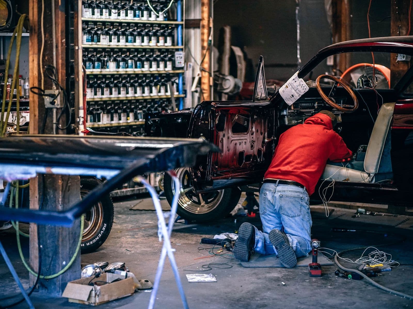 Mechanic kneeling beside a car in a restoration workshop
