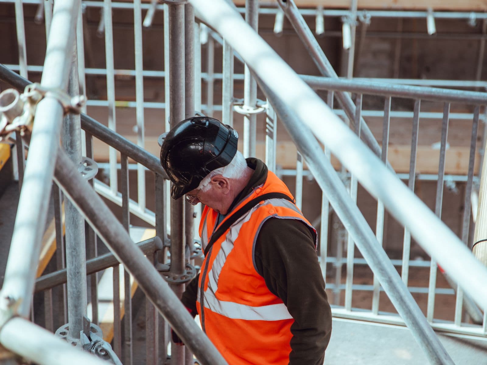 Contractor in a hard hat and safety vest working on scaffolding