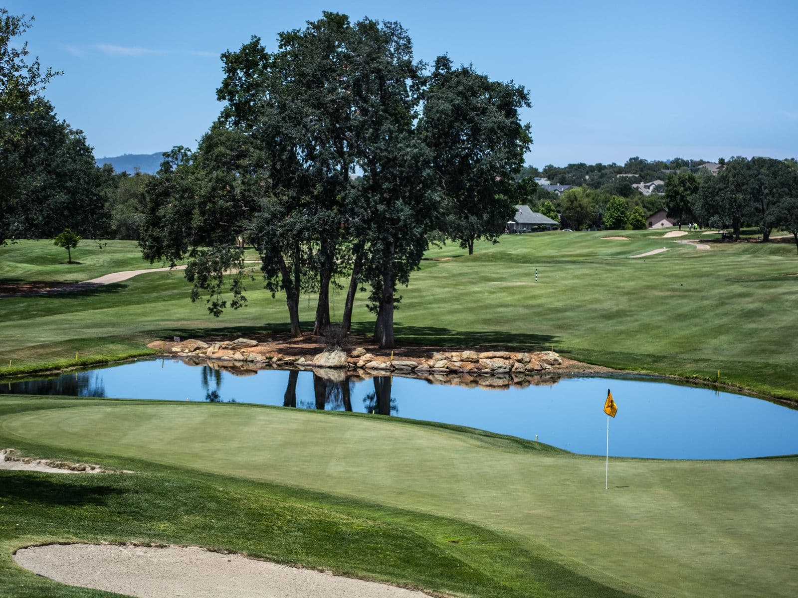 Fairway and green beside a pond on a sunny golf course