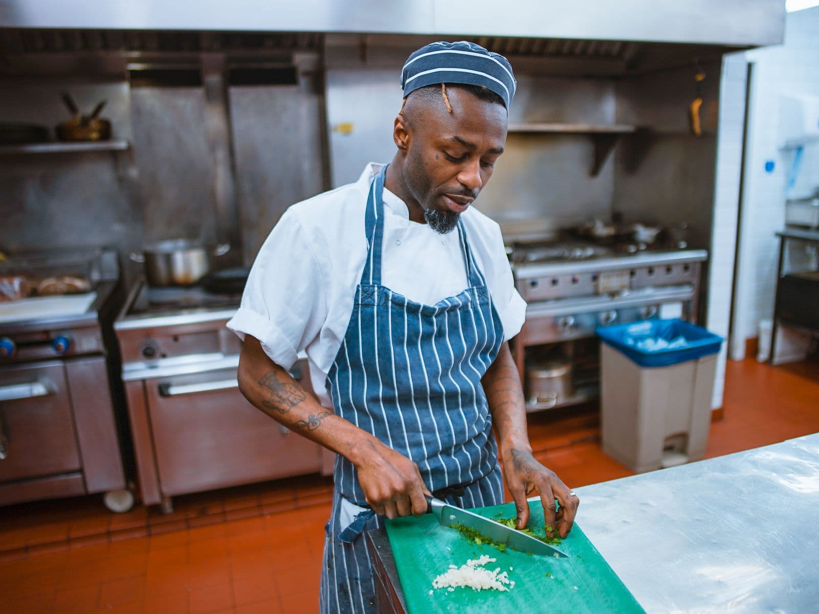 Chef prepping vegetables on a cutting board in a restaurant kitchen